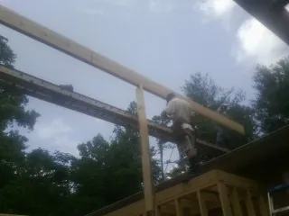 Carpenter setting a ridge beam over a new addition frame — Ice Dam Removal by Roofing Brothers in Bussey