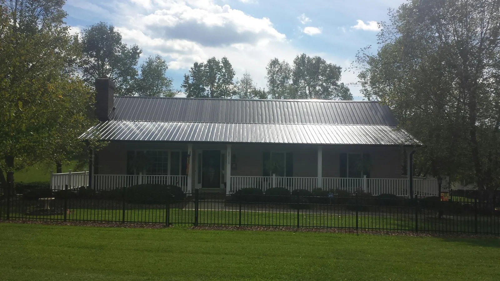 Gray metal roof on a brick ranch with a full width front porch — Gutter Guard Installation work by our crew in Bussey