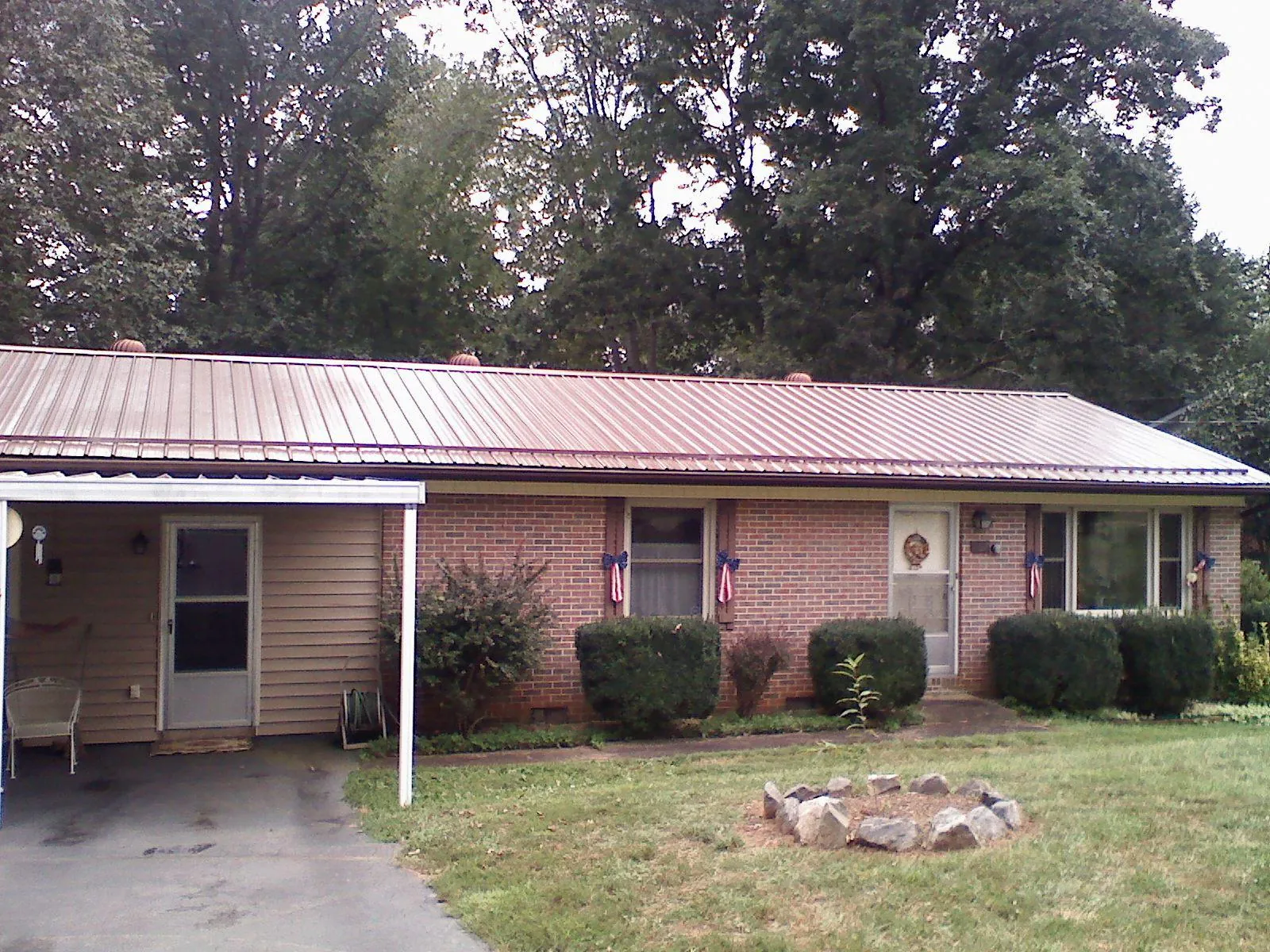 Bronze metal roof and carport on a brick ranch home — Roof Repair work by our crew in Bussey