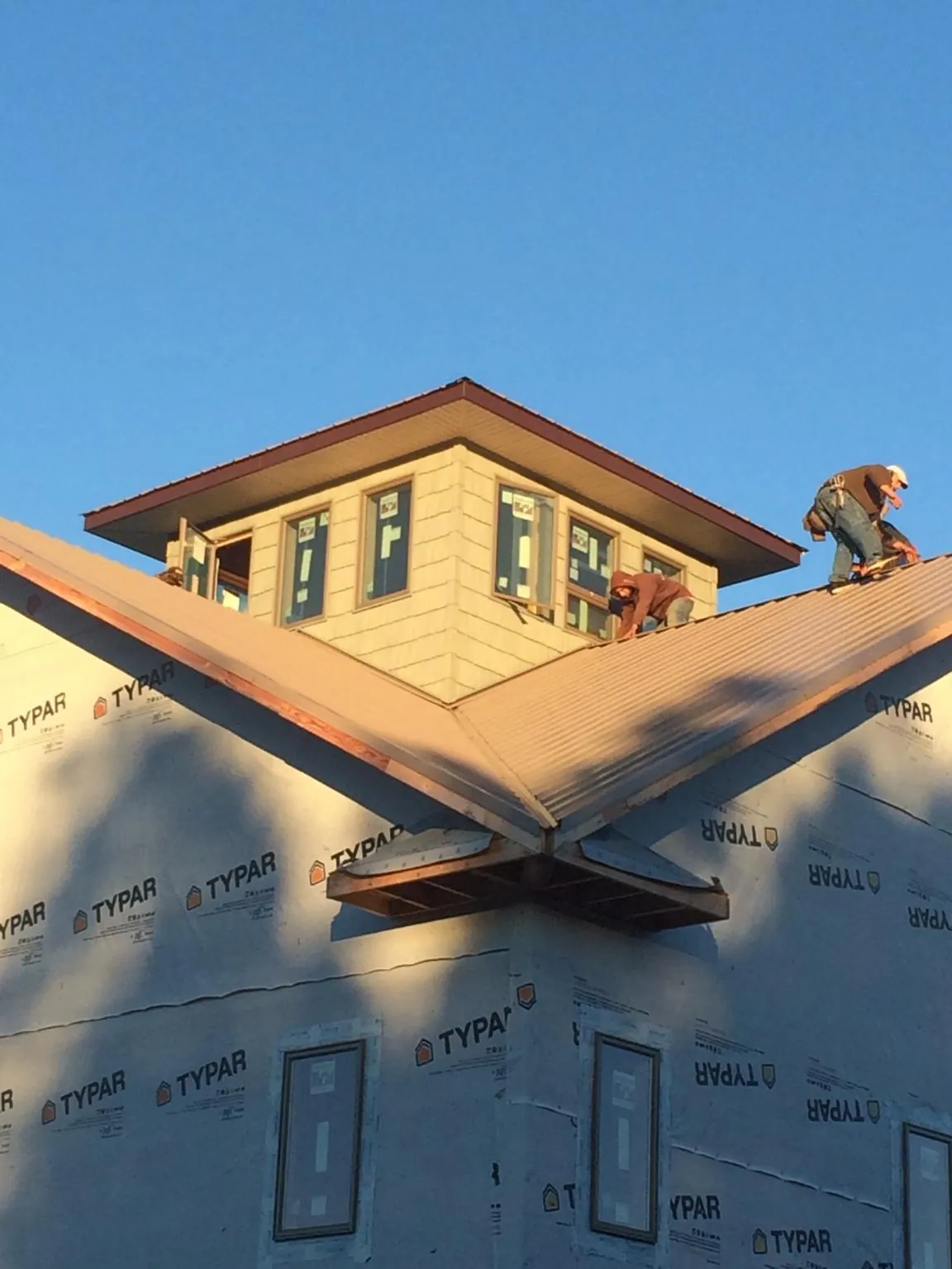 Roofers working around a rooftop cupola on a new metal roof at sunset — Roof Waterproofing in Bussey by Roofing Brothers